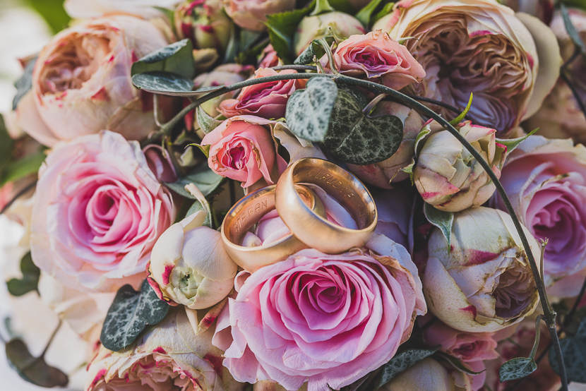 Anillos nupciales sobre ramo de bodas, parte crucial de un reportaje de boda en Sevilla.