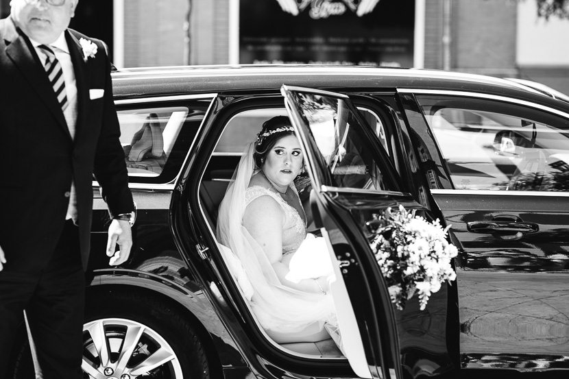 Novia bajandose del coche para dirigirse a la ceremonia de su boda en la iglesia del cachorro fotografiado por Bodas con Arte