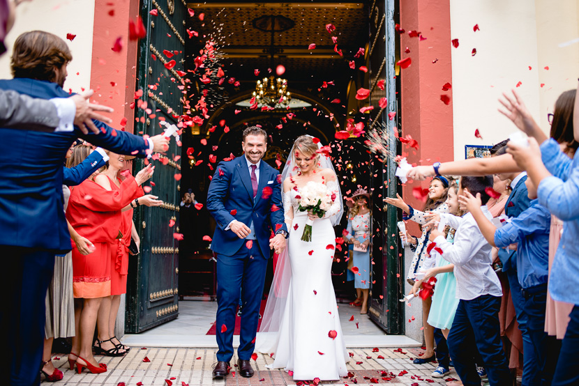 Invitados de una Boda en la Hermandad de los Negritos de Sevilla lanzando petalos a una pareja de recien casados, fotografía por Moisés García para Bodas con Arte, fotógrafo de bodas en Sevilla Este.